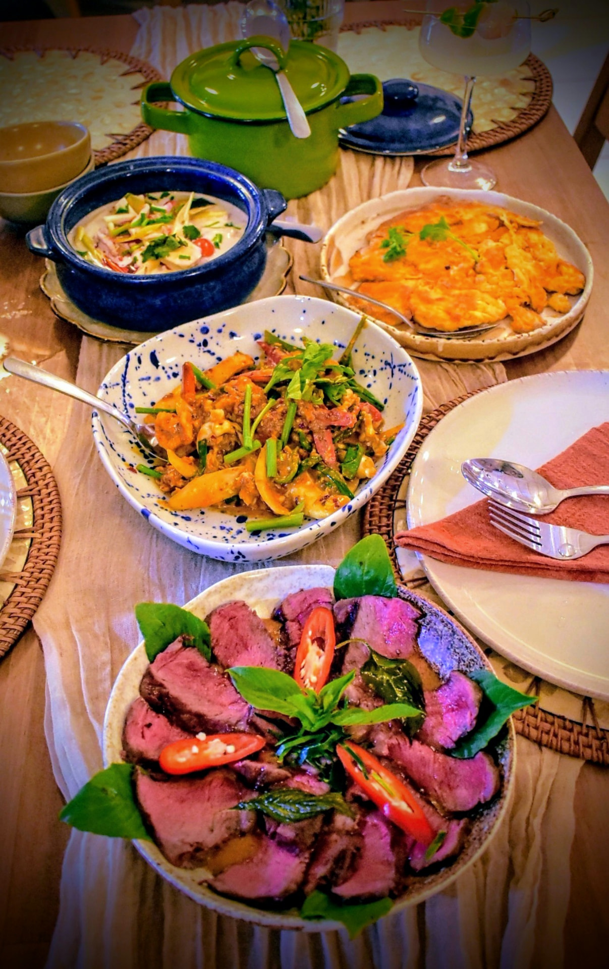 A table spread of Thai curries, omelette and sliced picanha steak