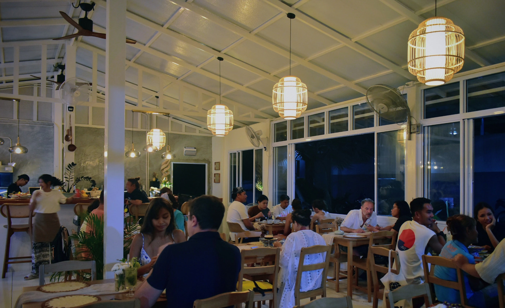 Open, airy dining room filled with guests at night